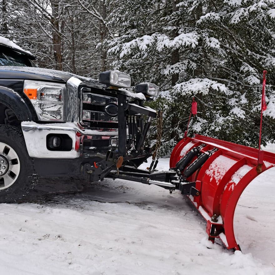 A pickup truck fitted with a plow blade on snow-covered ground
